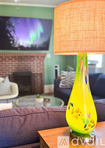 A yellow lamp with a green base is on a table in a living room.