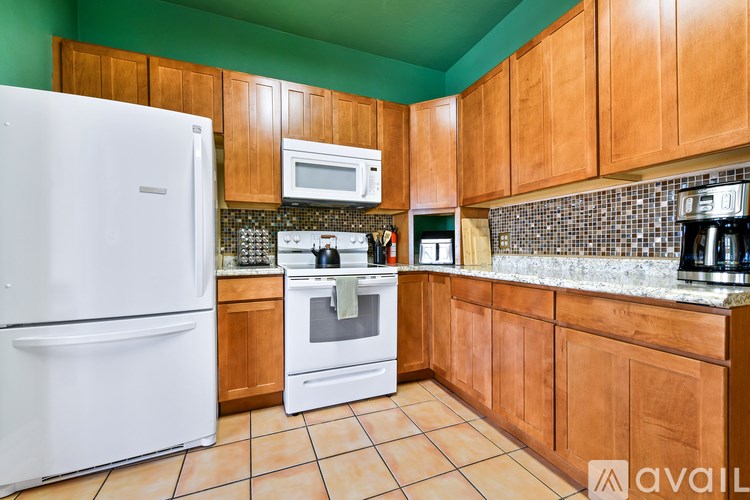 A kitchen with a white refrigerator, wooden cabinets, and a tiled backsplash.