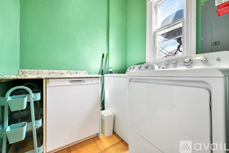 A white dishwasher is in a room with green walls.