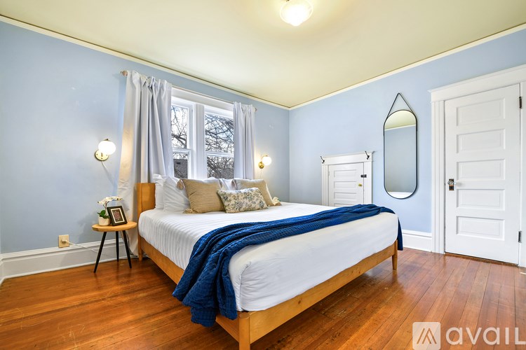 A bedroom with a bed, a mirror, and a window with curtains.