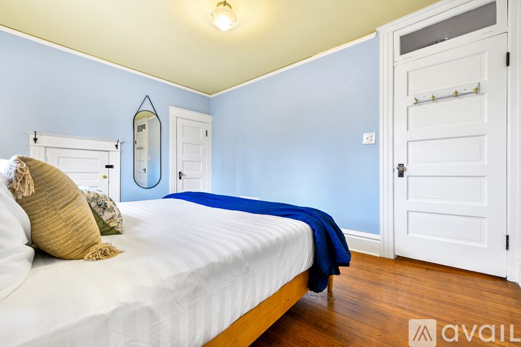 A bedroom with a bed, a mirror, and a door.