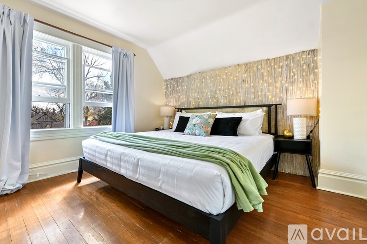 A bedroom with a bed, two lamps, and a window with curtains.