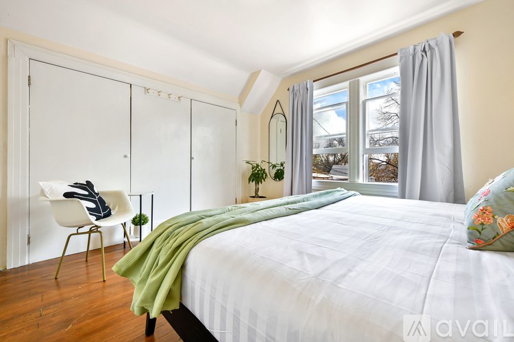 A bedroom with a bed, chair, and window.