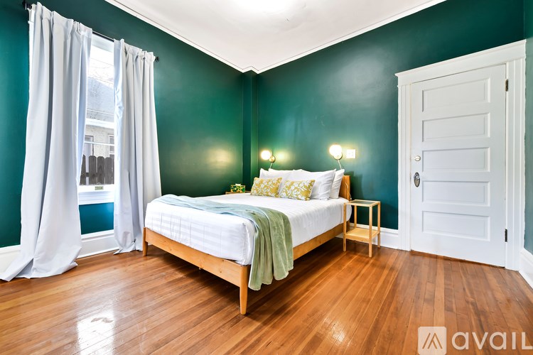 A bedroom with a bed, nightstand, and window.