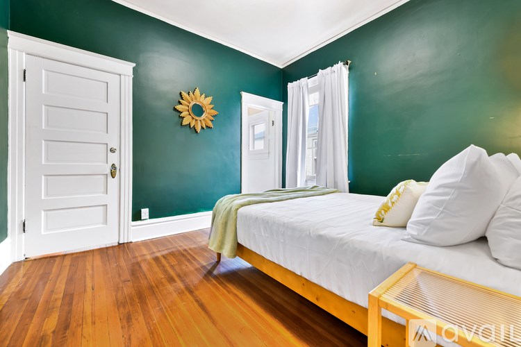 A bedroom with a bed, wooden floor, and a white door.