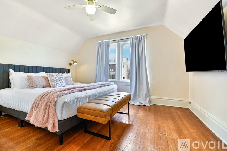 A bedroom with a large bed and a window with curtains.