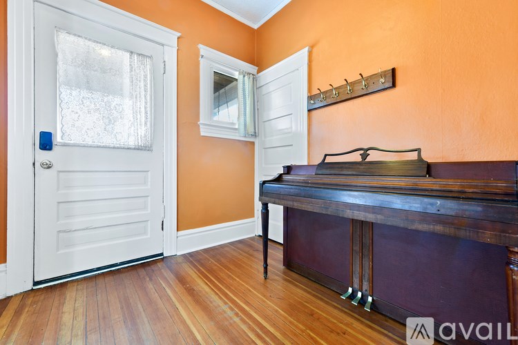 A room with a piano and a door with a window.