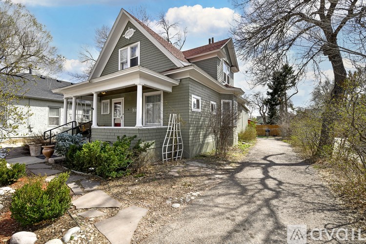 A house with a grey front and a brown roof with a small porch.
