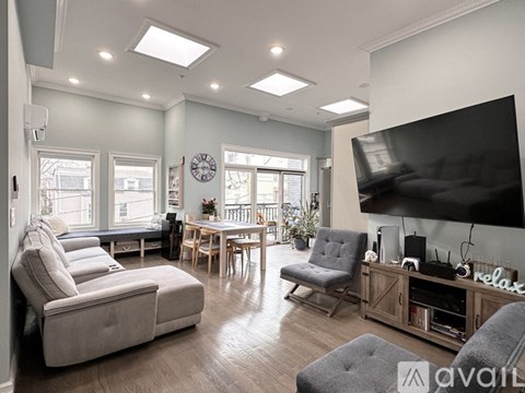 A living room with a grey sofa, a wooden table, and a television on the wall.