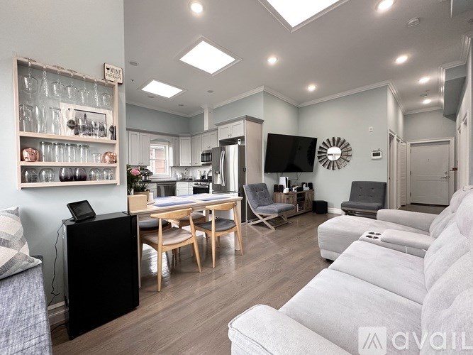 A modern living room with a kitchen area in the background.