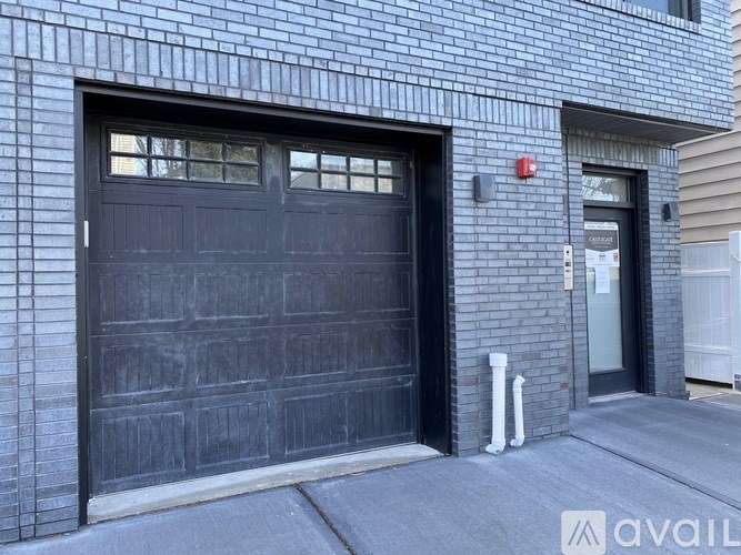 A black garage door is closed and there is a red light on the wall.
