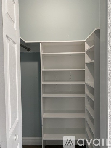 A white shelving unit with multiple shelves is in a room with a grey wall.