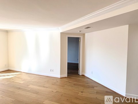 A room with wooden flooring and a doorway leading to another room.