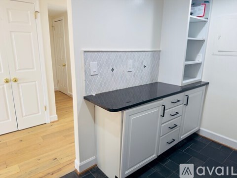 A kitchen with white cabinets and a black countertop.