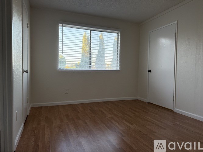A room with wooden flooring and a window with blinds.