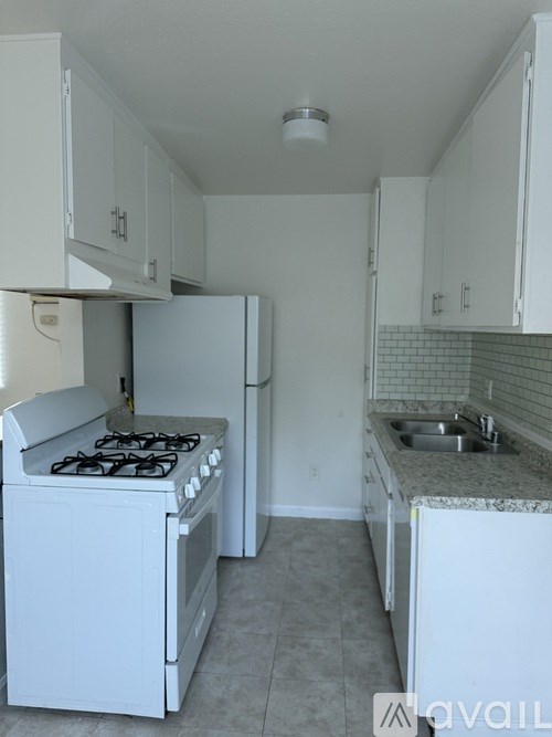 A kitchen with a white stove and cabinets.