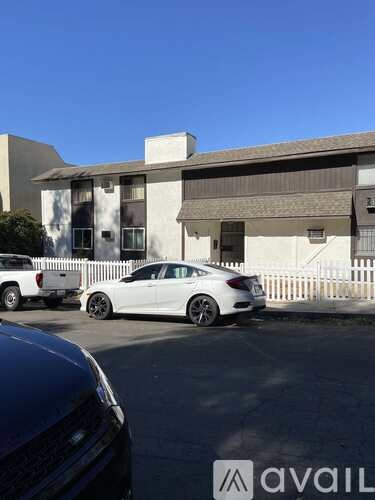 A white car is parked in front of a modern house.