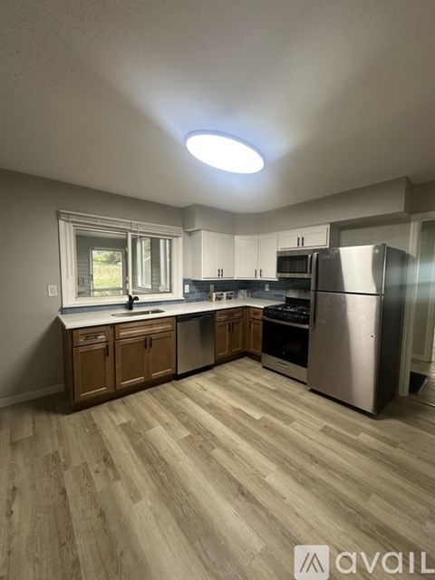 A kitchen with wooden cabinets and a stainless steel refrigerator.