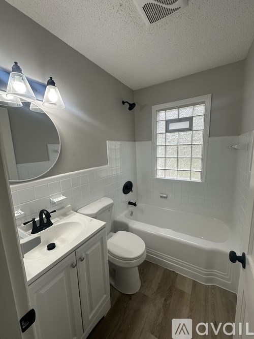 A bathroom with a white tub, sink, and toilet.