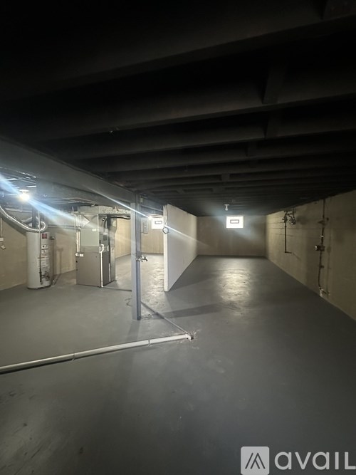 A spacious, empty industrial-style room with a bright light at the end of the hallway.