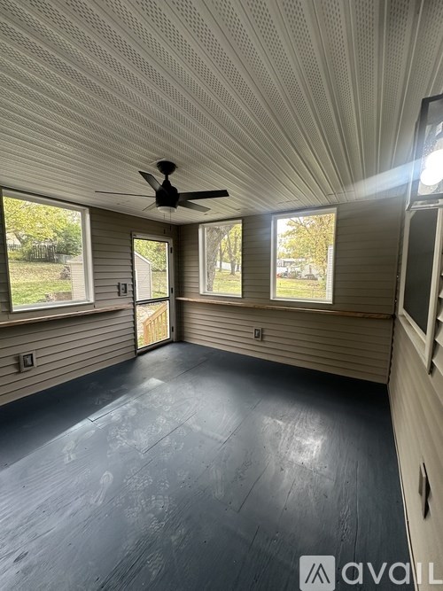 A room with a ceiling fan and three windows.