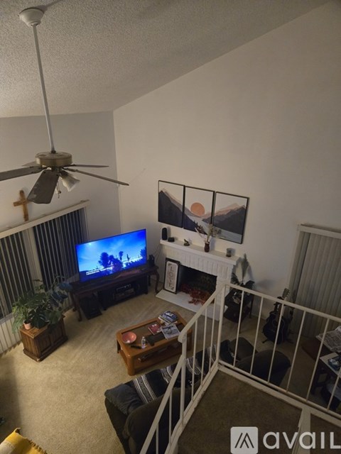A living room with a television, a fan, and a balcony.