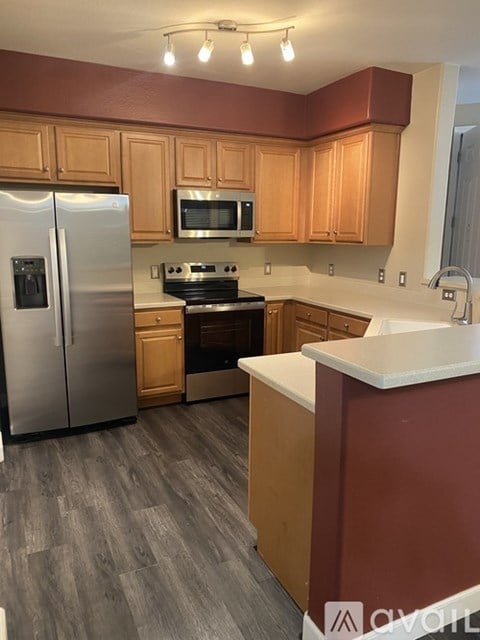 A kitchen with wooden cabinets and a stainless steel refrigerator.