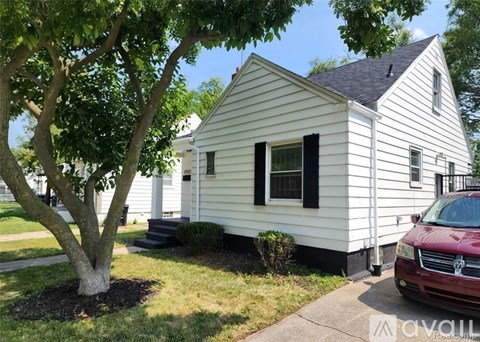 A white house with a red car parked in front.