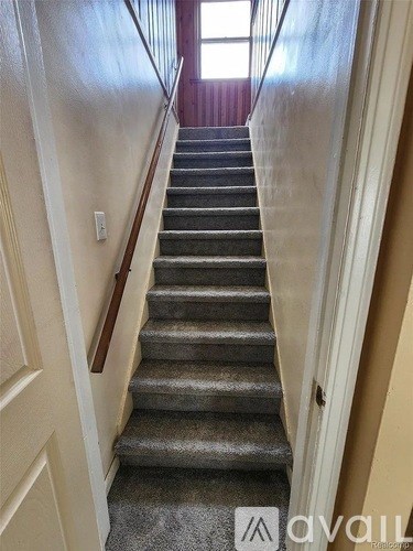 A staircase with a carpeted runner and wooden handrails.