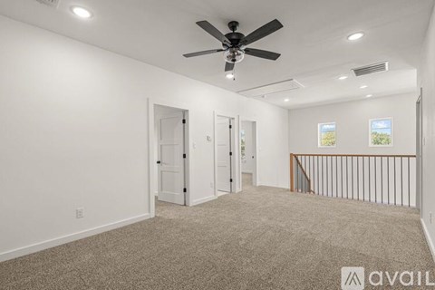 A spacious room with a ceiling fan and carpeted floor.