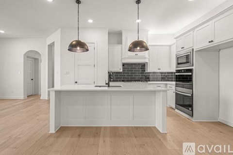 A modern kitchen with a center island and pendant lights.