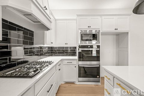 A modern kitchen with white cabinets and stainless steel appliances.