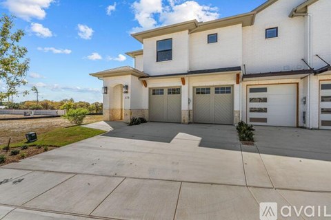 A modern two-story house with a large driveway in front.