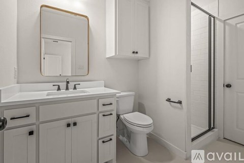 A bathroom with a white toilet, sink, and cabinets.