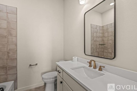 A bathroom with a toilet, sink, and mirror.