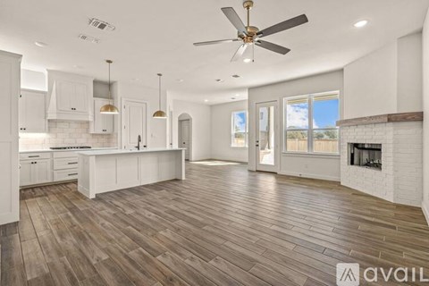 A spacious kitchen with white cabinets and a wooden floor.