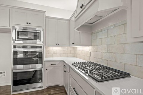 A modern kitchen with a stainless steel oven and a white backsplash.