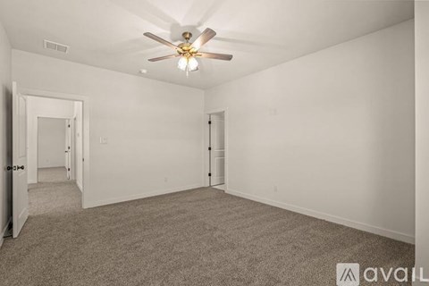 A spacious room with a ceiling fan and carpeted floor.