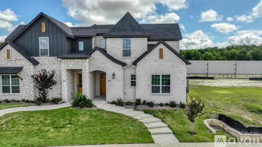 A large, modern house with a stone facade and a dark roof.