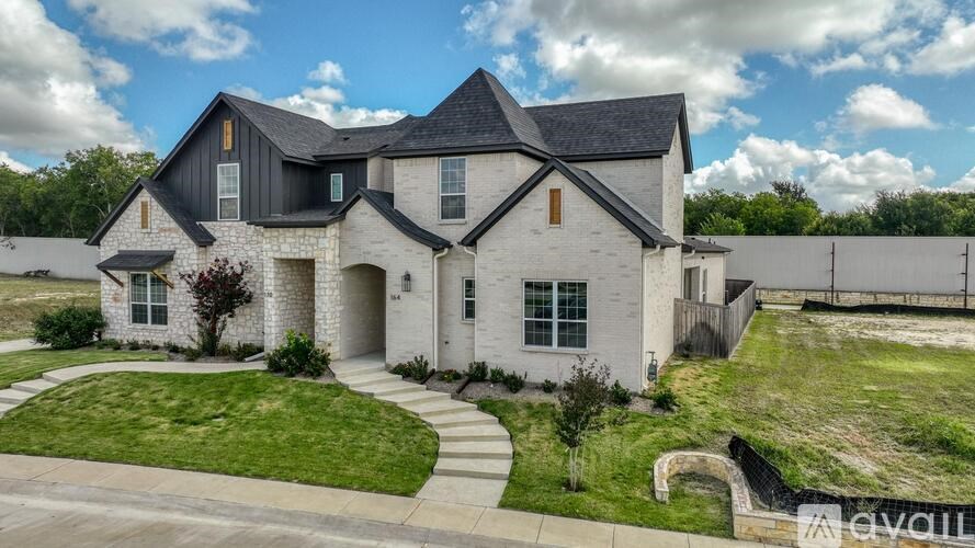 A modern house with a large front yard and a driveway.