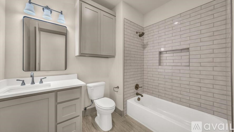 A white toilet sits in a bathroom with a white sink and a white bathtub.