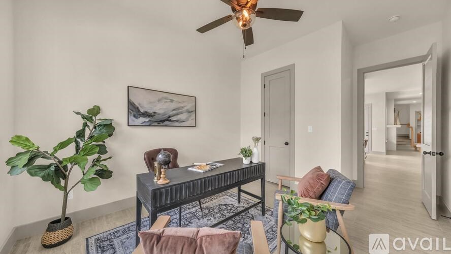 A living room with a ceiling fan and a painting on the wall.