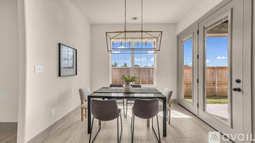 A dining room with a table set for two and a view of a backyard through the window.