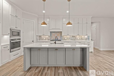 A modern kitchen with a large island and wooden flooring.