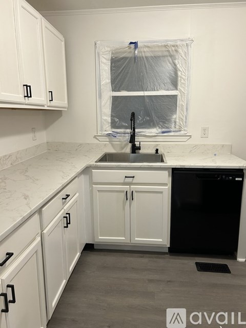 A kitchen with white cabinets and a black dishwasher.