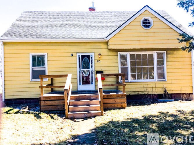 A yellow house with a white door and windows.