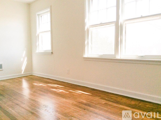 A room with wooden floors and two windows.