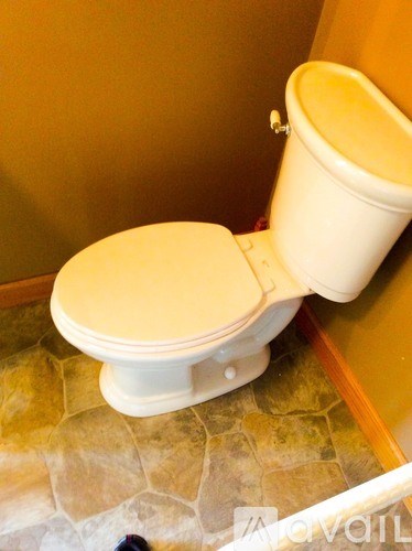 A white toilet with a white tank is installed in a bathroom with a stone floor.