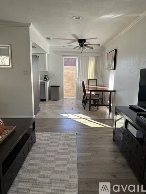 A living room with a dining table and chairs, a kitchen area with a refrigerator, and a television.