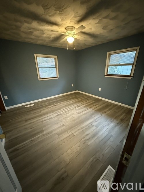 A room with wooden floors and two windows.